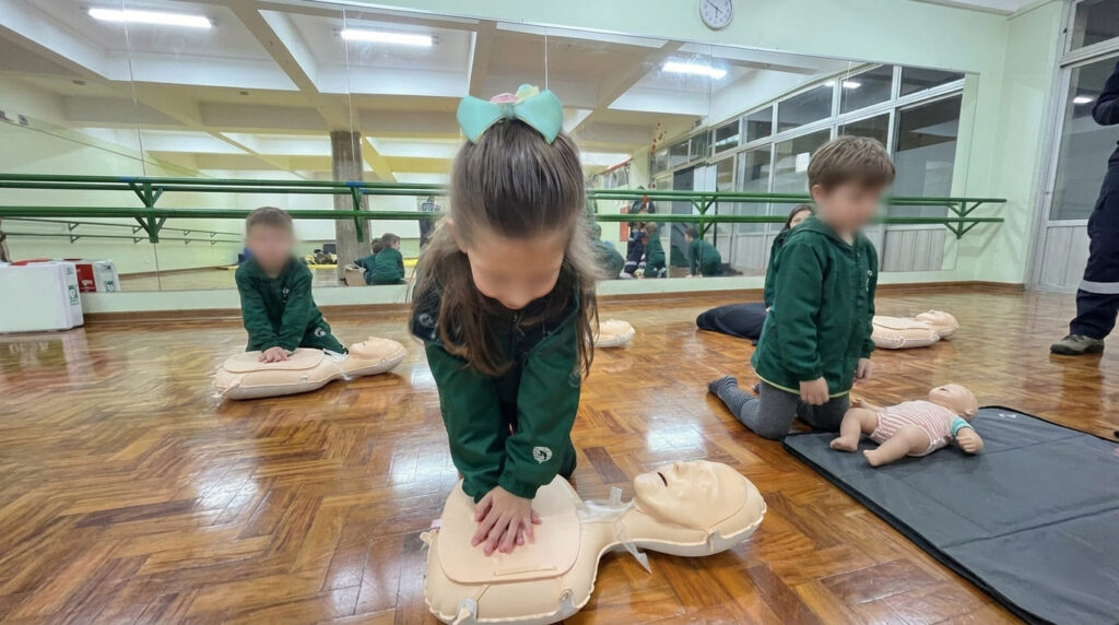Crianças praticando primeiros socorros com manequins no projeto CTS